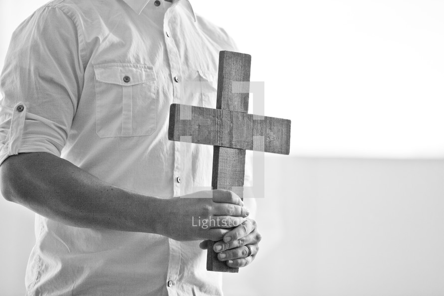 man holding a wooden cross at his chest
