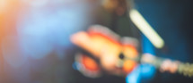 blurry image of a man on stage playing a guitar 