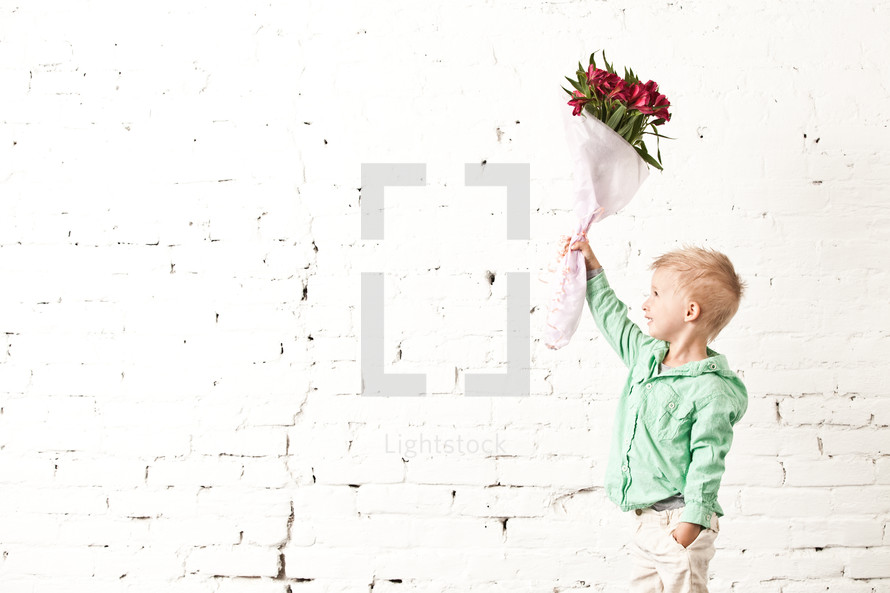 boy holding up a bouquet of flowers