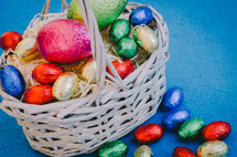 colored easter eggs in a basket on a blue background
