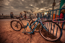 Bicycles in a bike rack at a busy beach.