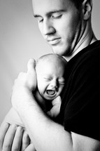father holding a crying newborn
