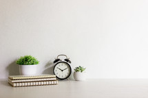 Minimal concept with notebooks, clock and cactus on wooden table with natural light. 