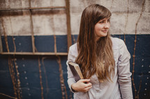 a young woman holding a Bible 