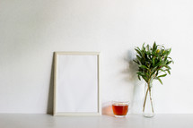 frame, tea cup, and olive branches in a vase 
