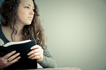 Teenage girl in thought holding open Bible.