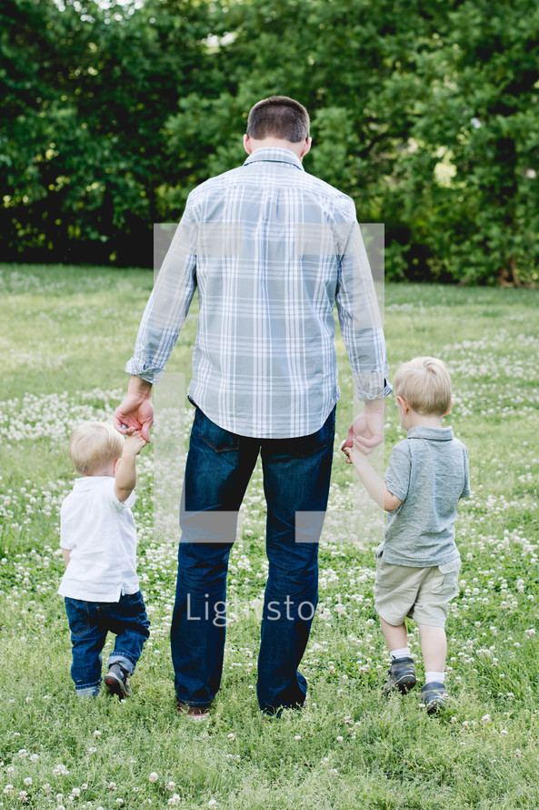 a father walking in a field with his sons 