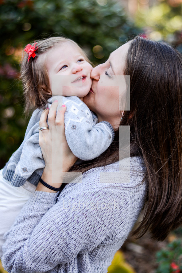 a mother kissing her toddler girl 