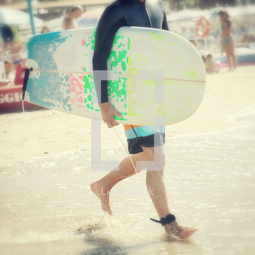 man walking on a beach carrying a surfboard 
