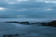 Ocean waves and rocks at dusk.