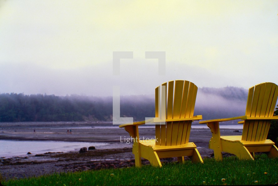 Adirondack chairs on a shore 