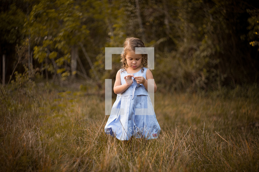 a toddler girl standing in tall grasses 