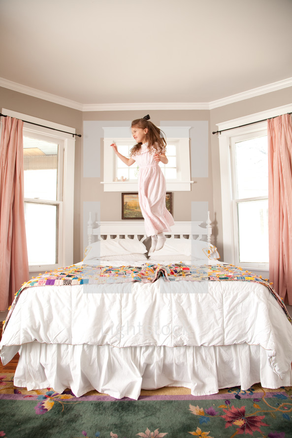 little girl jumping on the bed
