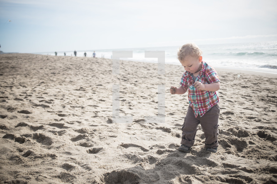 toddler boy walking in the sand 
