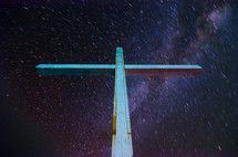 A cross stands amid the night sky with the background of stars and arm of our  galaxy.