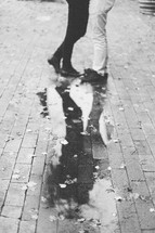 reflection of a couple hugging in a puddle on patio brick 