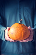 Man holding a decorated orange Pumpkin in both hands