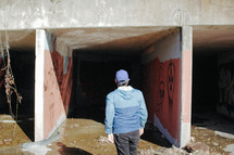man walking under a concrete overpass 