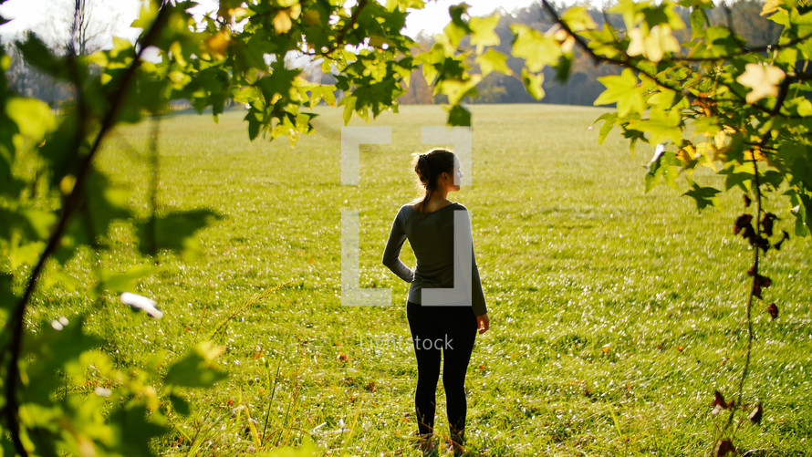 woman standing in a field of cut green grass 