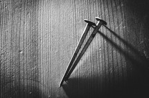 A b&w shot of two nails on a wooden background