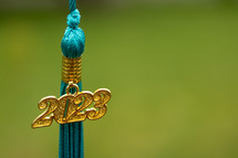 a gold and teal tassel with a green background