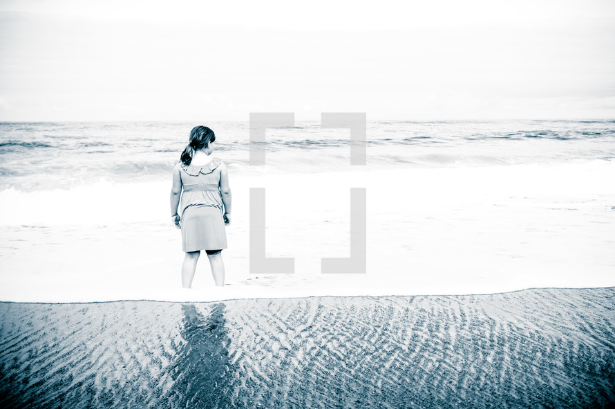 woman standing in water on beach in a dress 
