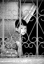Child playing behind iron window