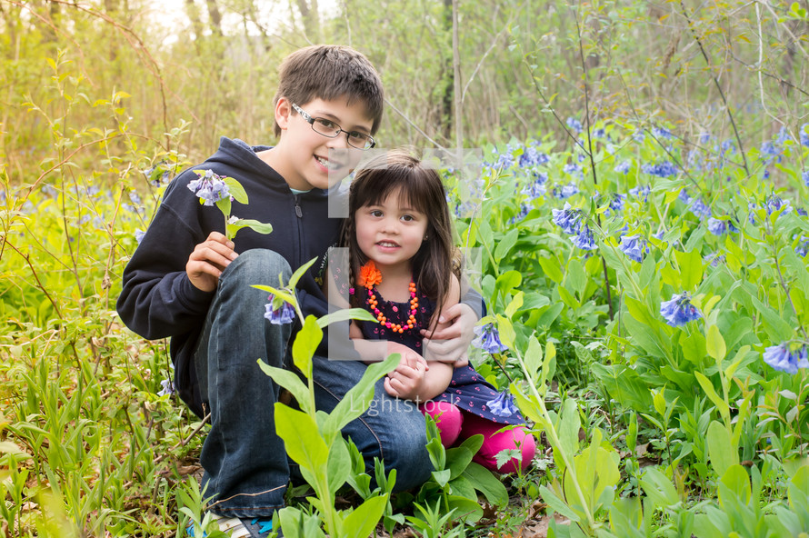 Young boy and small girl, sitting among wild flowers