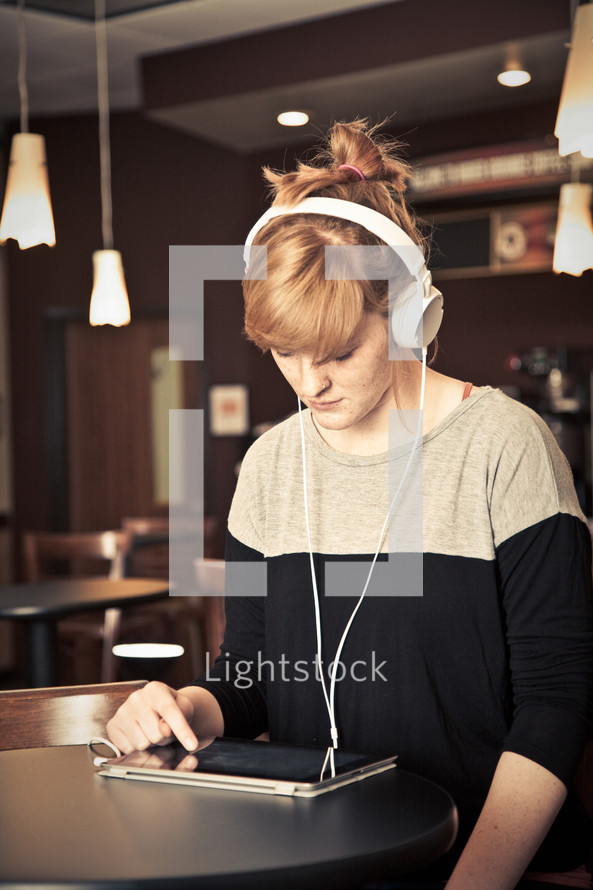 woman in headphones looking at an iPad