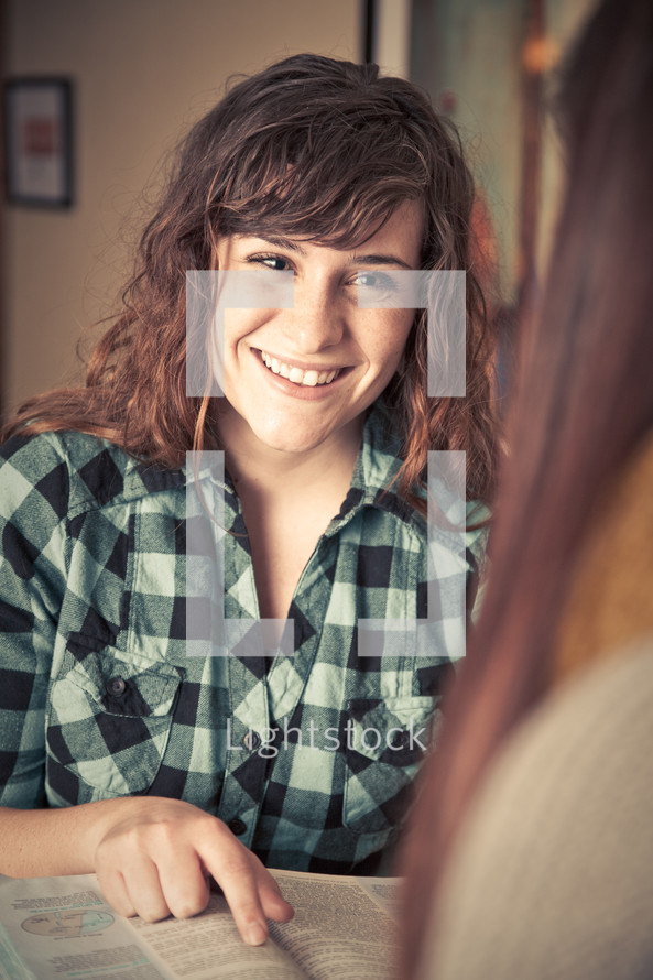 young woman pointing to Bible scripture and smiling 