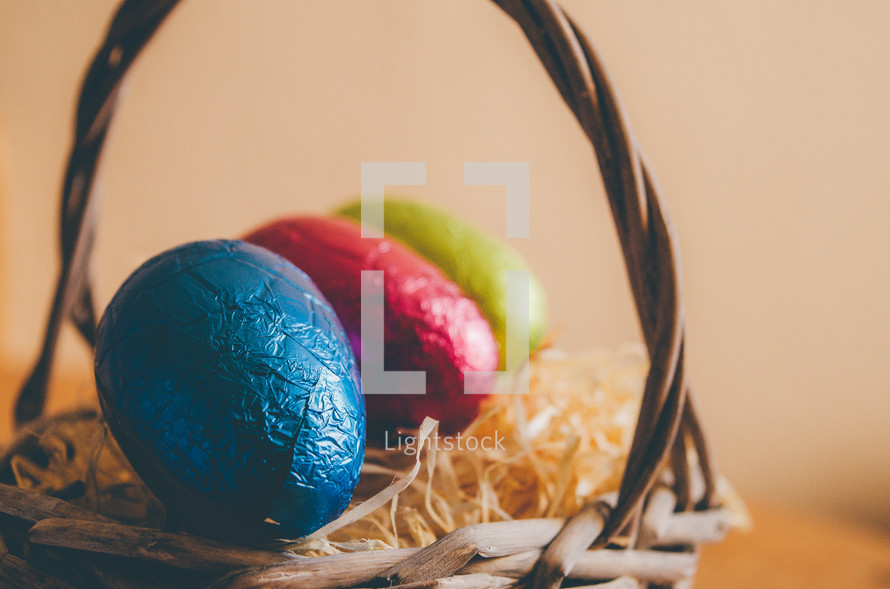 Colored easter eggs in a wicker basket on a table
