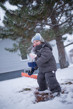 a boy child shoveling snow