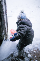 a boy child shoveling snow in a doorway 