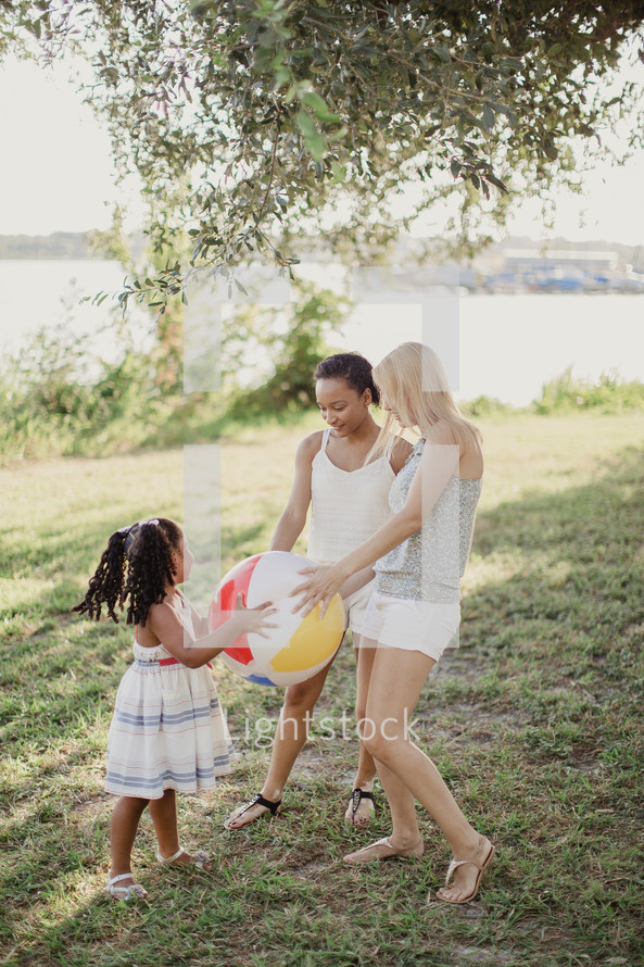 Two young women and a little girl playing with a beach ball.