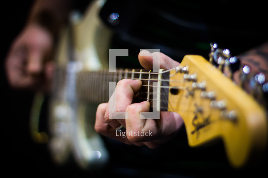 man's hands playing an electric guitar 