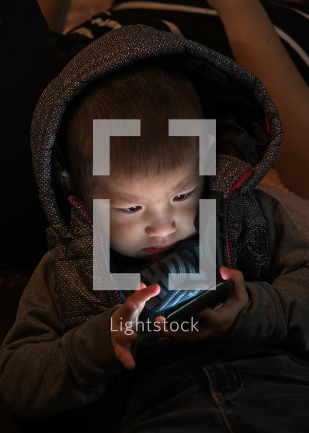 toddler boy looking at a cellphone screen 