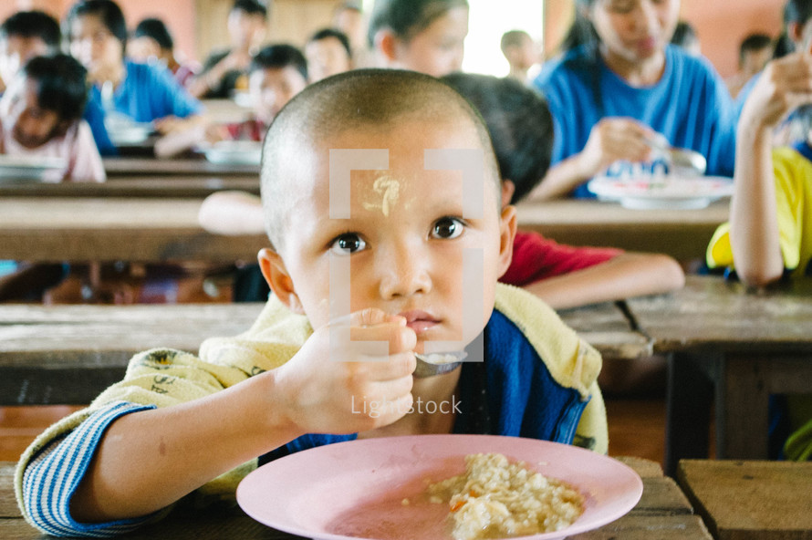children in an orphanage eating in a cafeteria 