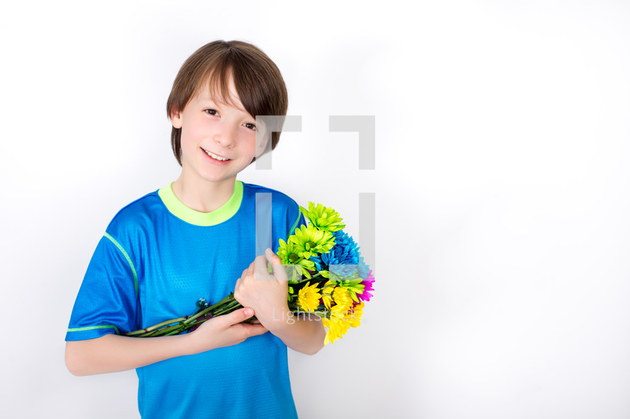 Smiling boy cradling a bouquet of flowers.