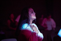 a woman with hands over her heart during a worship service 