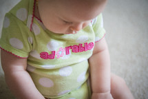 an infant in a onesie looking down 