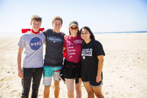 group of smiling teens standing on a beach 
