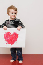 boy child holding a Valentine's picture of a heart 