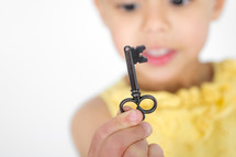 Large black key being held by a little girl