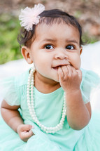 an infant girl chewing her fingers 