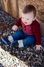 a toddler boy sitting in rocks 