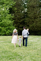 A family walking through a meadow of green grass.