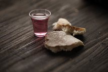 Communion bread and wine on a wood table.