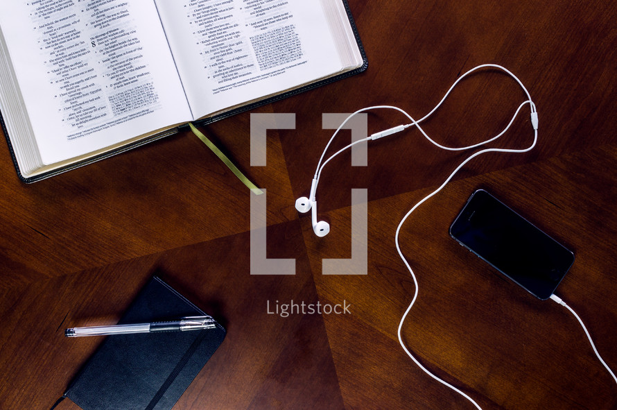 open Bible, earbuds, podcast, table, Bible, cellphone, ipod, mp3 player, pen, journal, scripture 