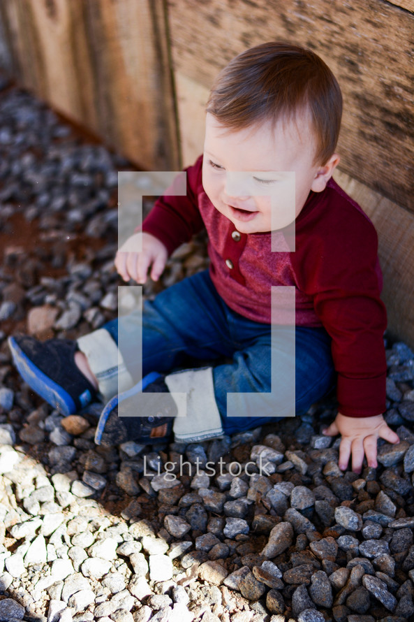 a toddler boy sitting in rocks 