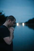 a man in praying in front of a reflection pool 